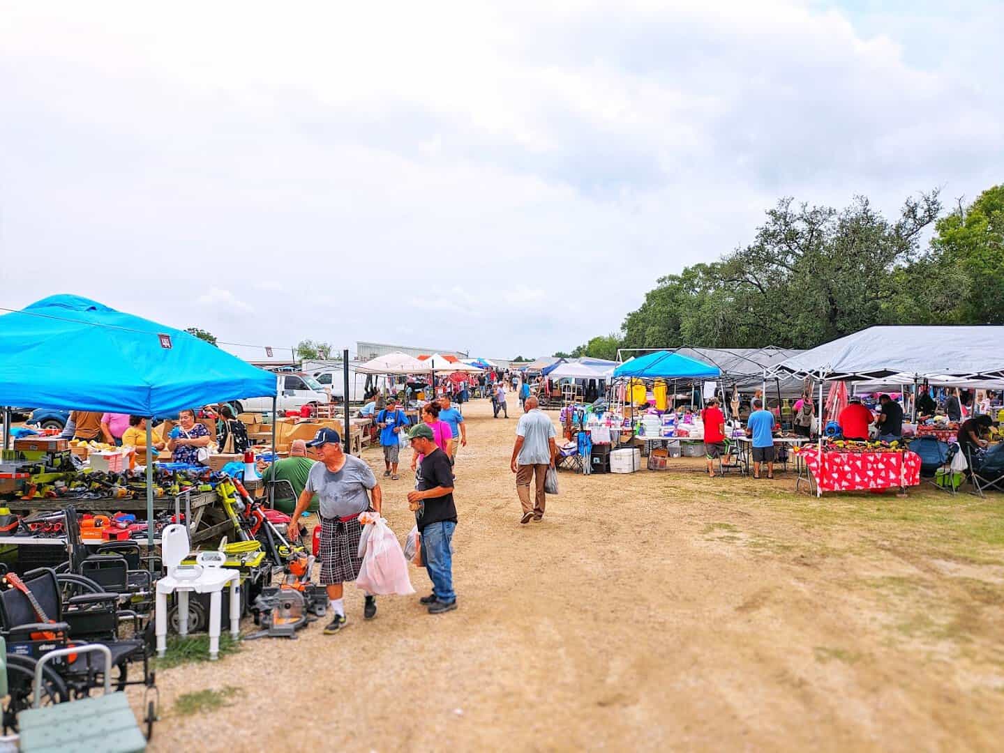 Tool tables and canopy stalls spread across the open field at Cole's flea market in Pearland, Texas