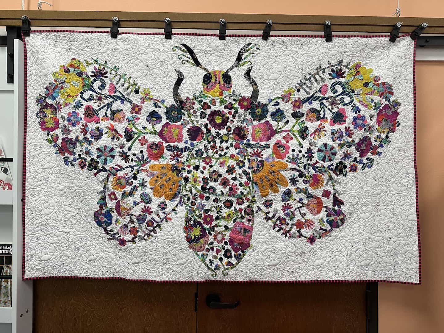 A colorful floral butterfly applique quilt on display at Quilt Country in Lewisville, Texas