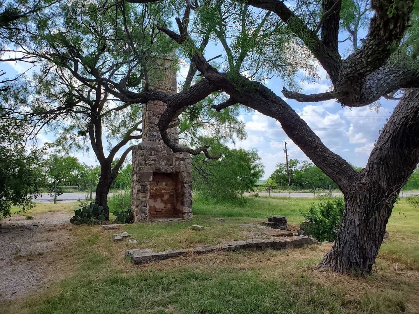 Stone chimney framed by an oak tree at Fort Phantom Hill