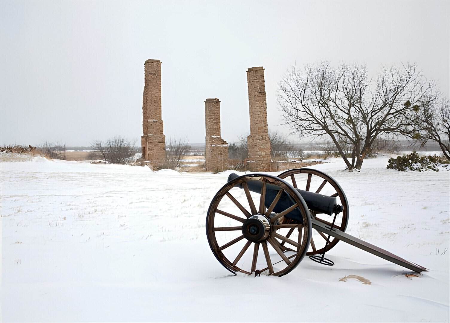 Stone chimneys and a cannon in winter at Fort Phantom Hill