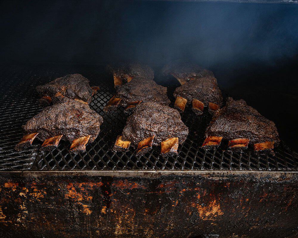 Brisket and ribs smoking on the pit at Franklin Barbecue in Austin, Texas