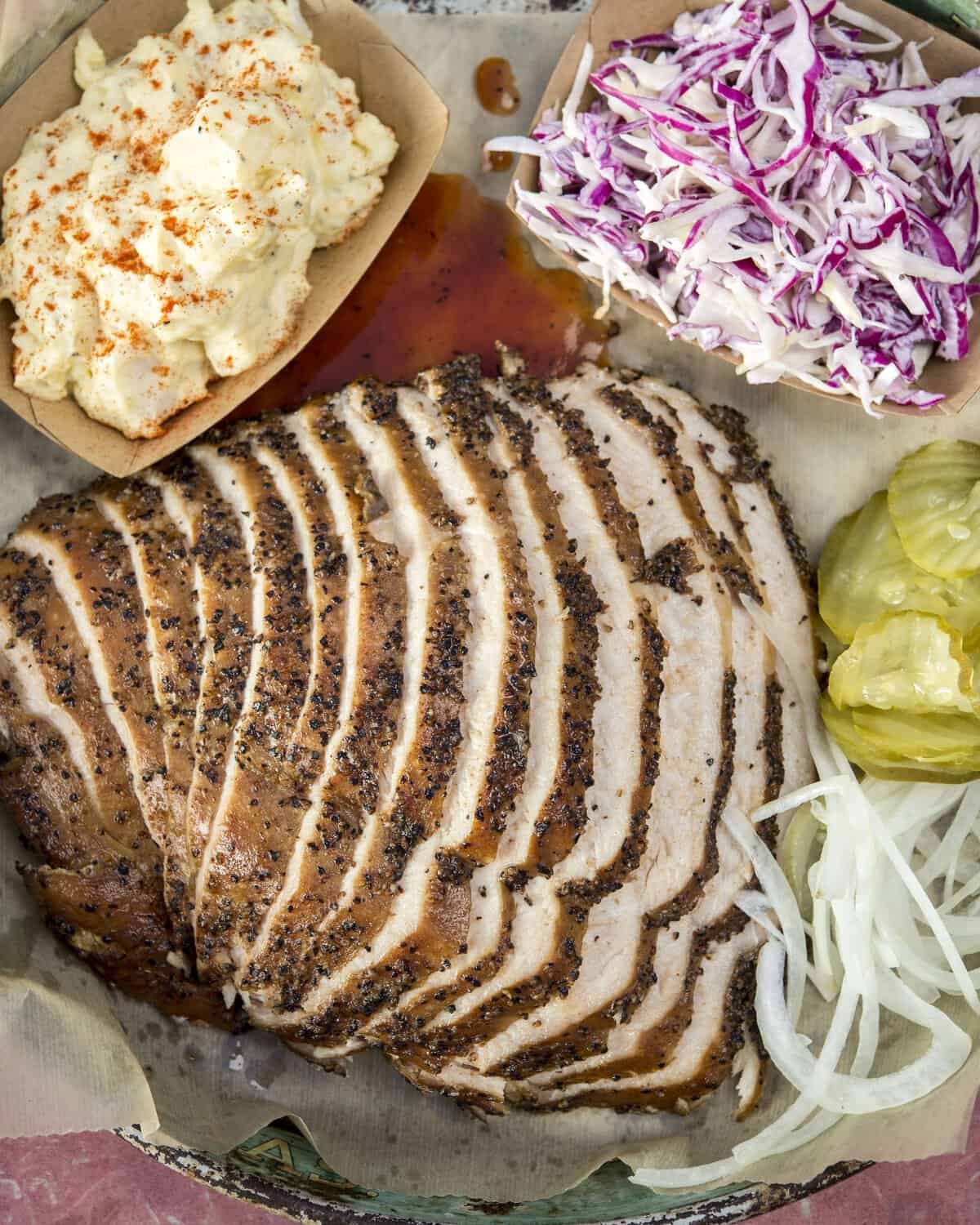 Sliced peppery smoked brisket with pickles and onions at Franklin Barbecue in Austin, Texas
