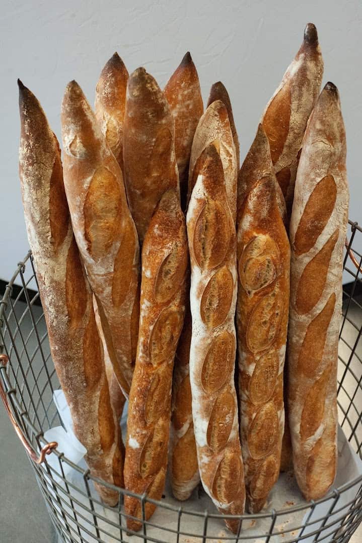 Fresh-baked baguettes standing in a basket at Artisana Bread in Houston, Texas