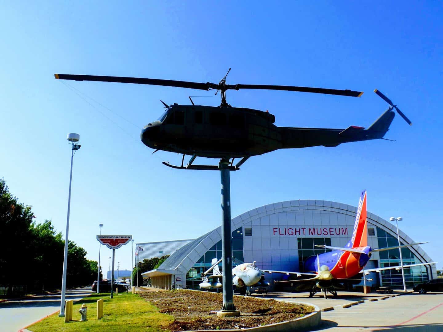 The entrance and sign of the Frontiers of Flight Museum in Dallas with a helicopter monument
