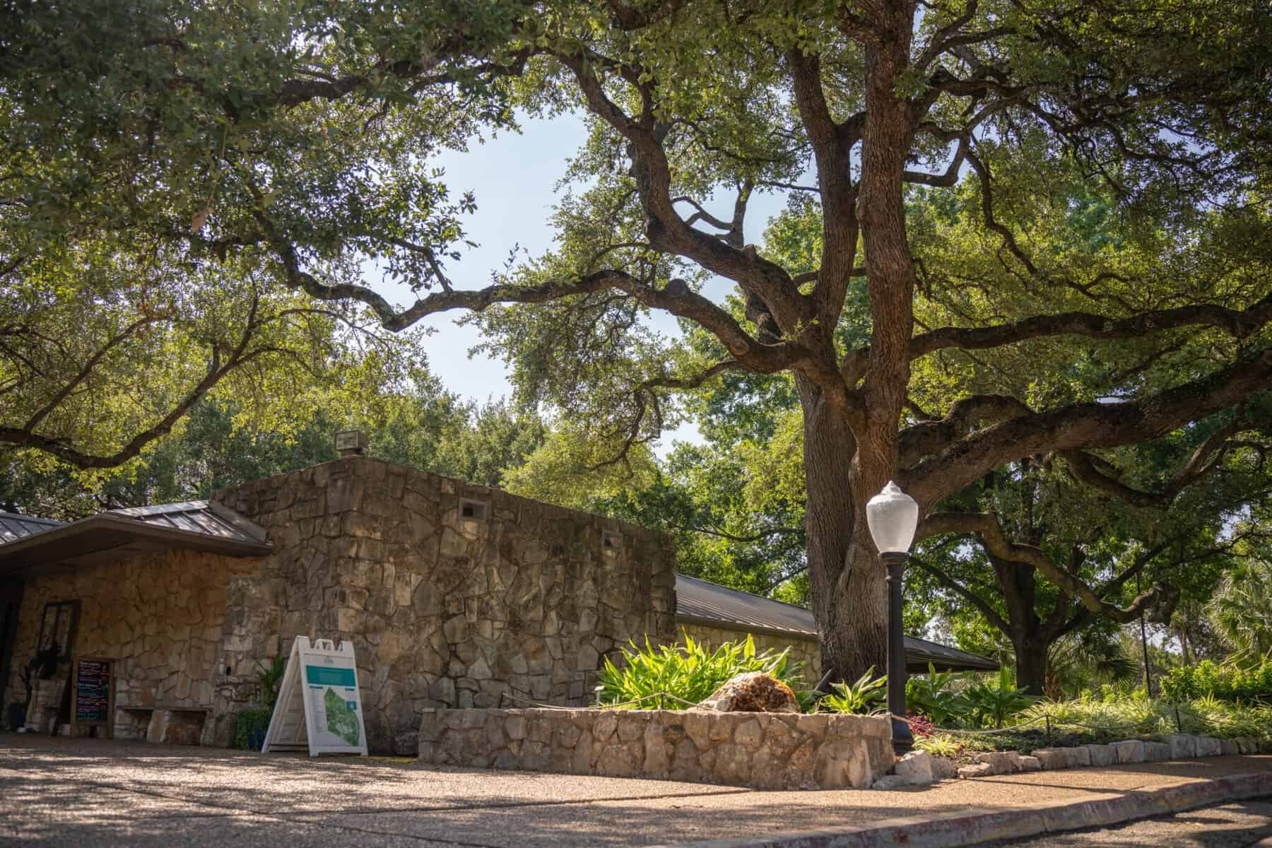 The stone Austin Area Garden Center building under a live oak at Zilker Botanical Garden in Austin, Texas
