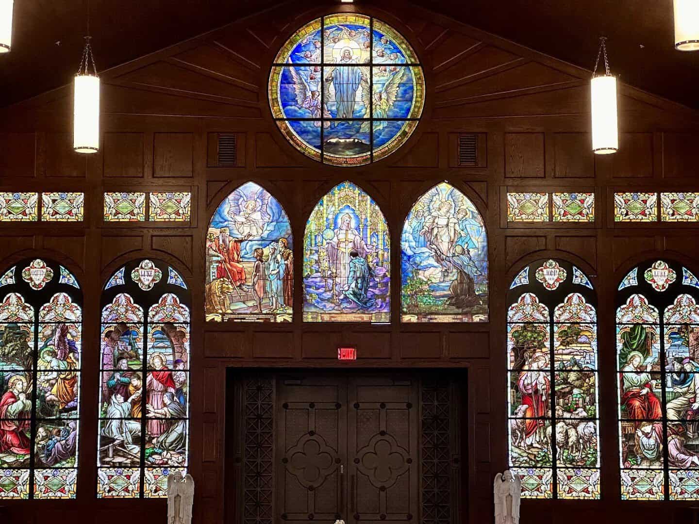 Chapel with a blue stained glass window and hanging lamps at the Gelman Stained Glass Museum