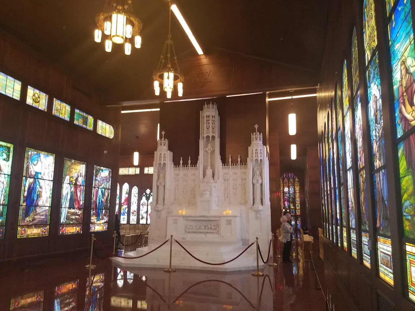 A gallery of stained-glass windows with a marble statue at the end