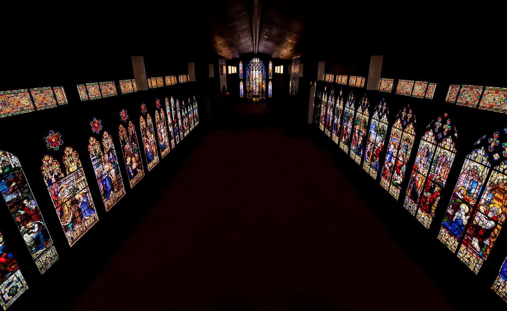 Stained-glass windows lining the museum hall, reflected in the polished granite floor