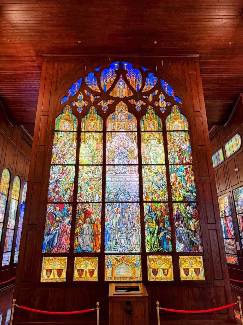 Towering Tiffany stained glass window with religious figures at the Gelman Stained Glass Museum