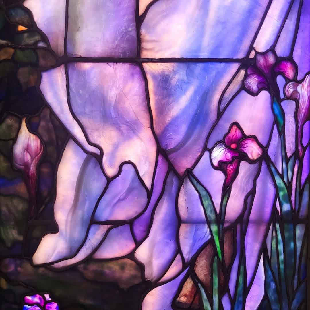 Close-up of a purple Tiffany opalescent stained glass window with irises at the Gelman Stained Glass Museum
