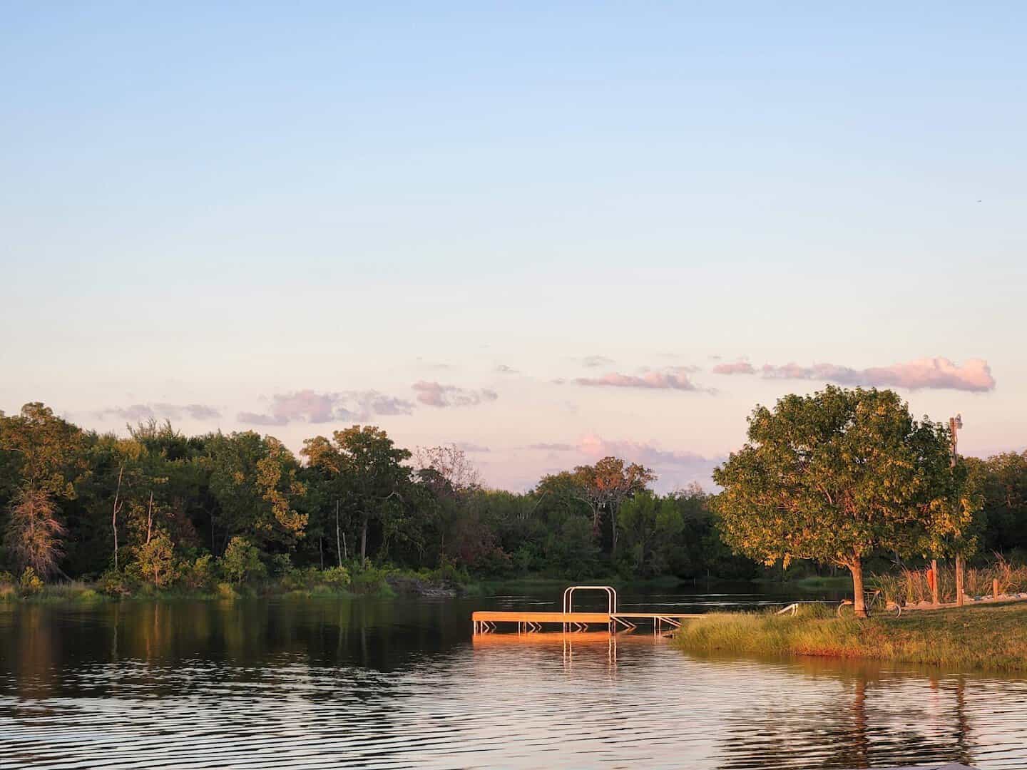 Golden hour view of the lakefront and a small dock at Purtis Creek State Park