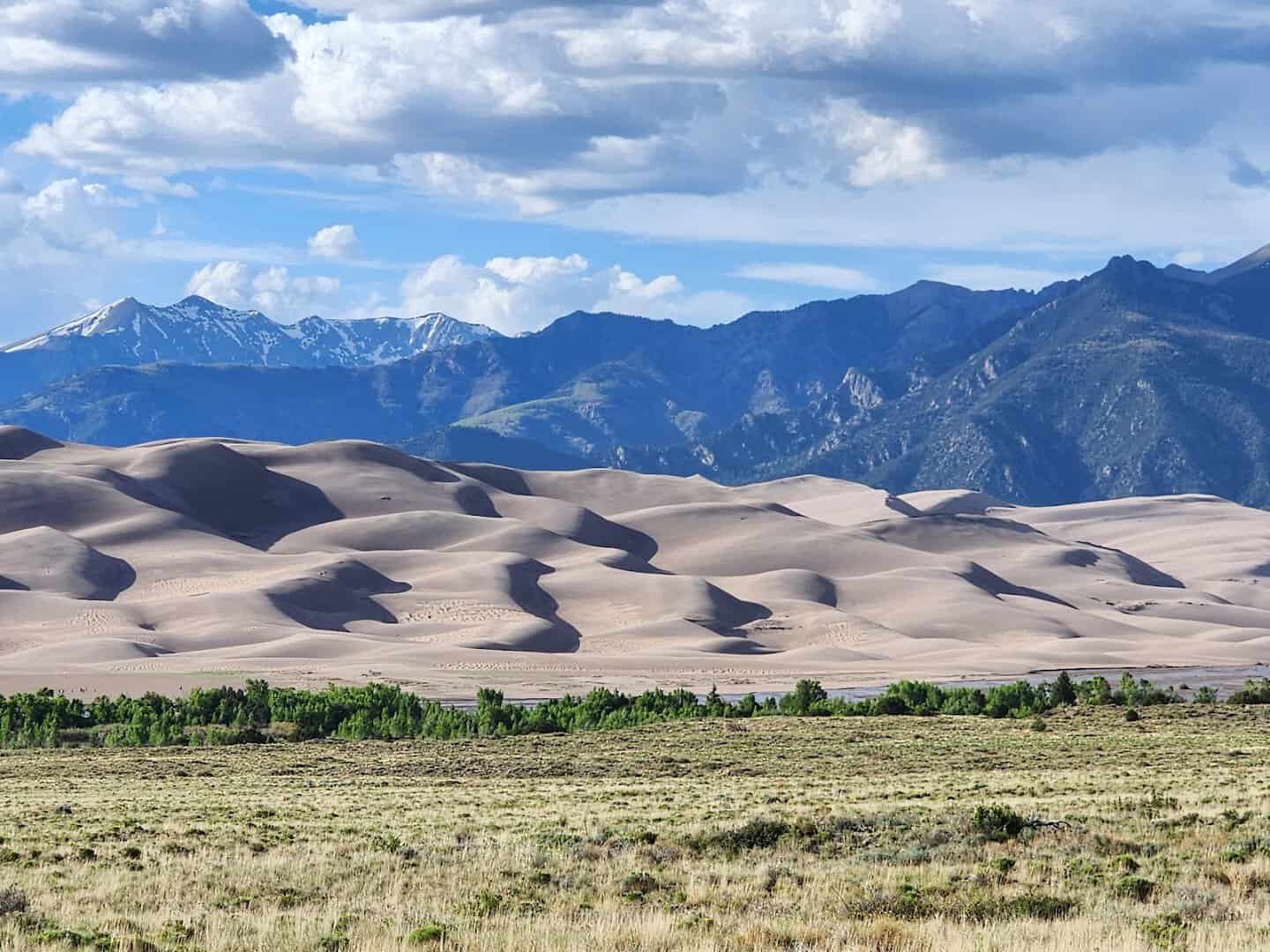 Great Sand Dunes rising against snowcapped mountains, Colorado