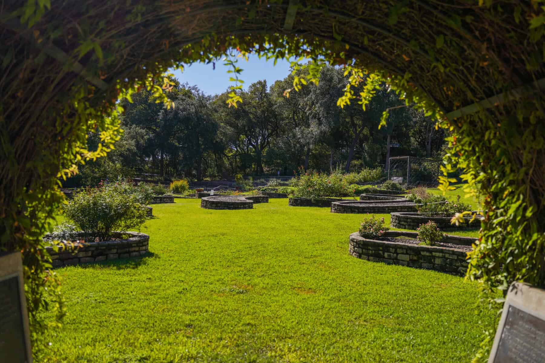 A green lawn seen through a stone arch at Zilker Botanical Garden in Austin, Texas