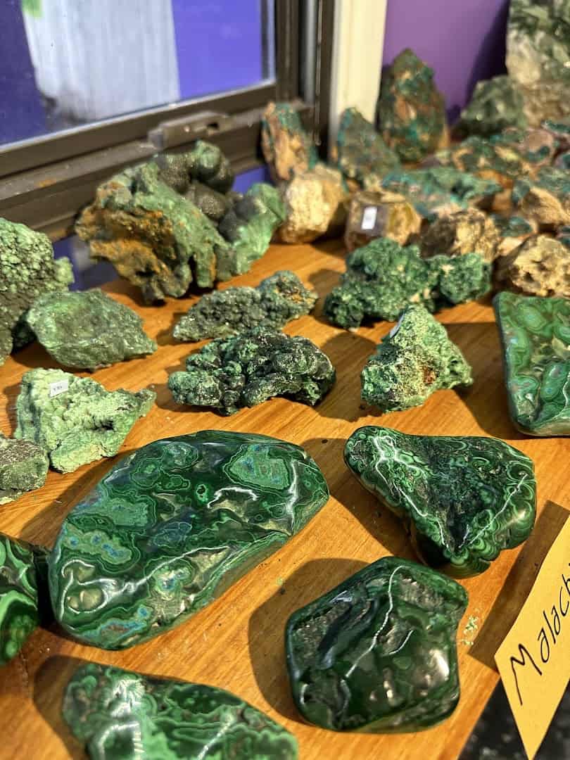 Raw green malachite specimens on a wood display at Shiny Things For Shiny People in Austin