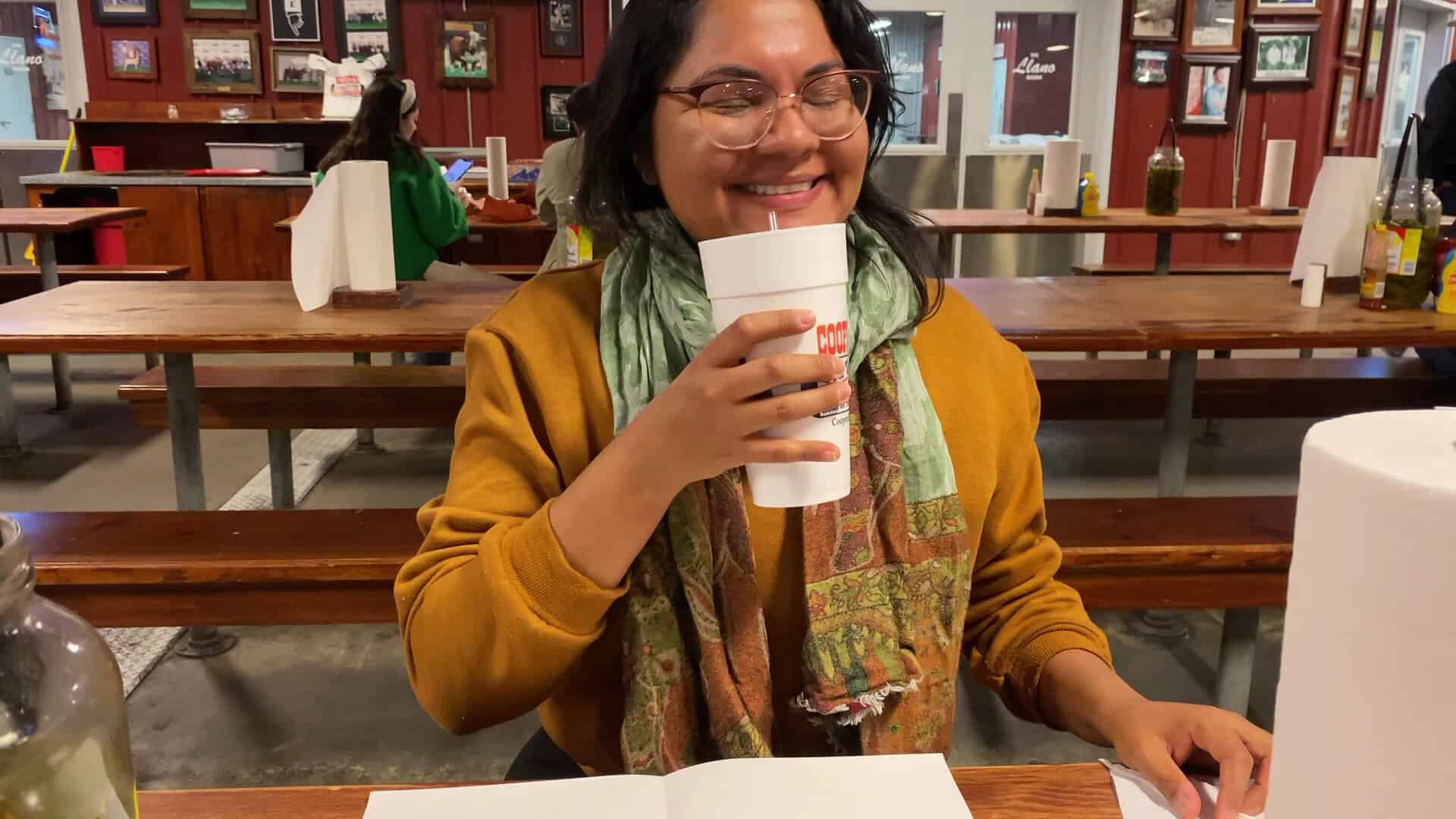 A guest enjoying a drink at a communal table inside Cooper's in Fort Worth