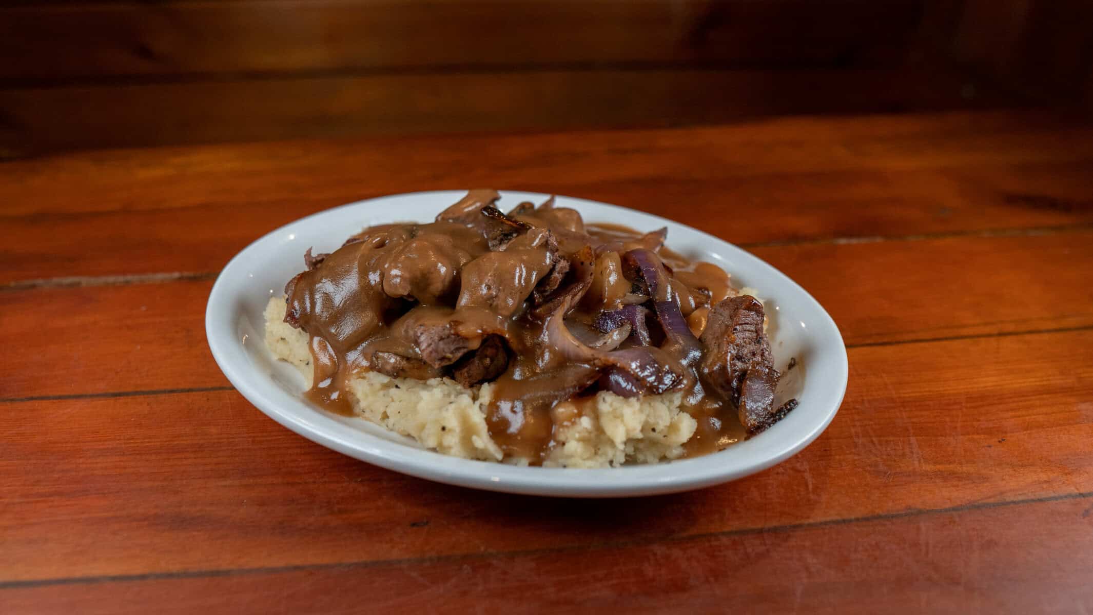 Beef tips in gravy with grilled onions over mashed potatoes at Hofbrau Steaks in Porter, Texas