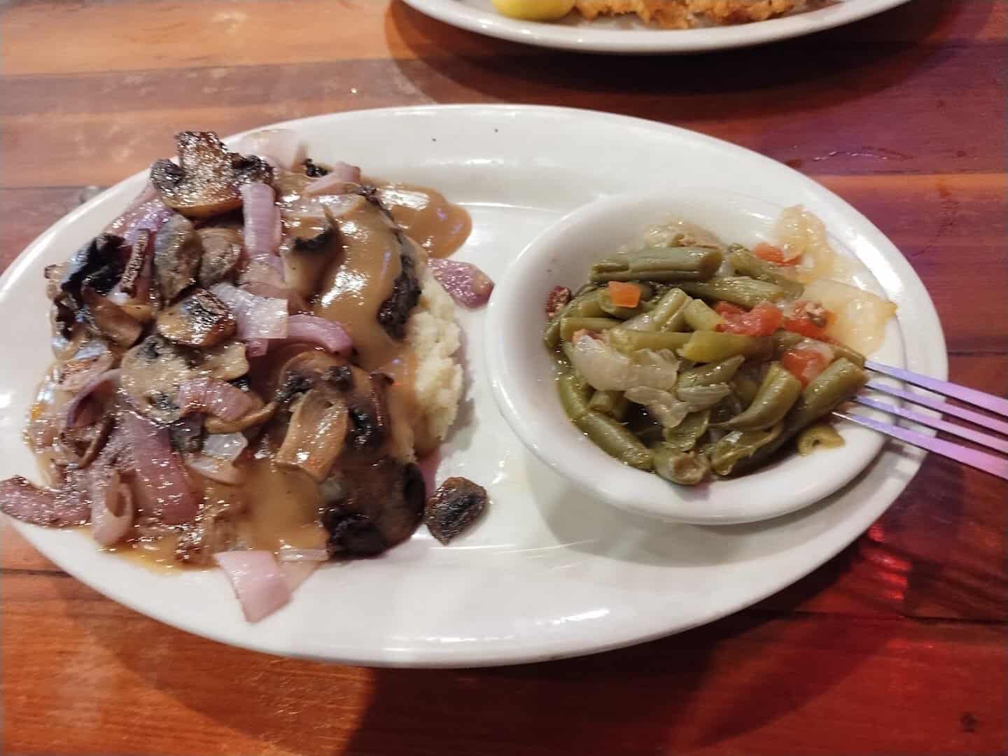 Hamburger steak under grilled onions and gravy with green beans at Hofbrau Steaks in Porter, Texas