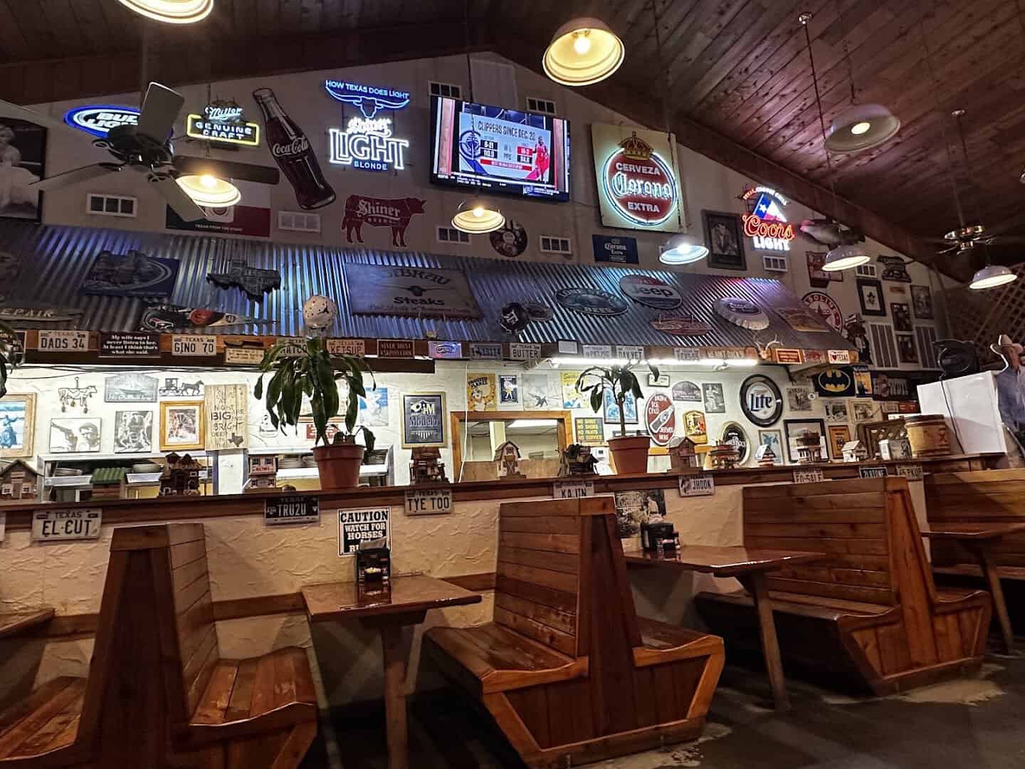 Wooden booths and neon signs in the dining room at Hofbrau Steaks in Porter, Texas