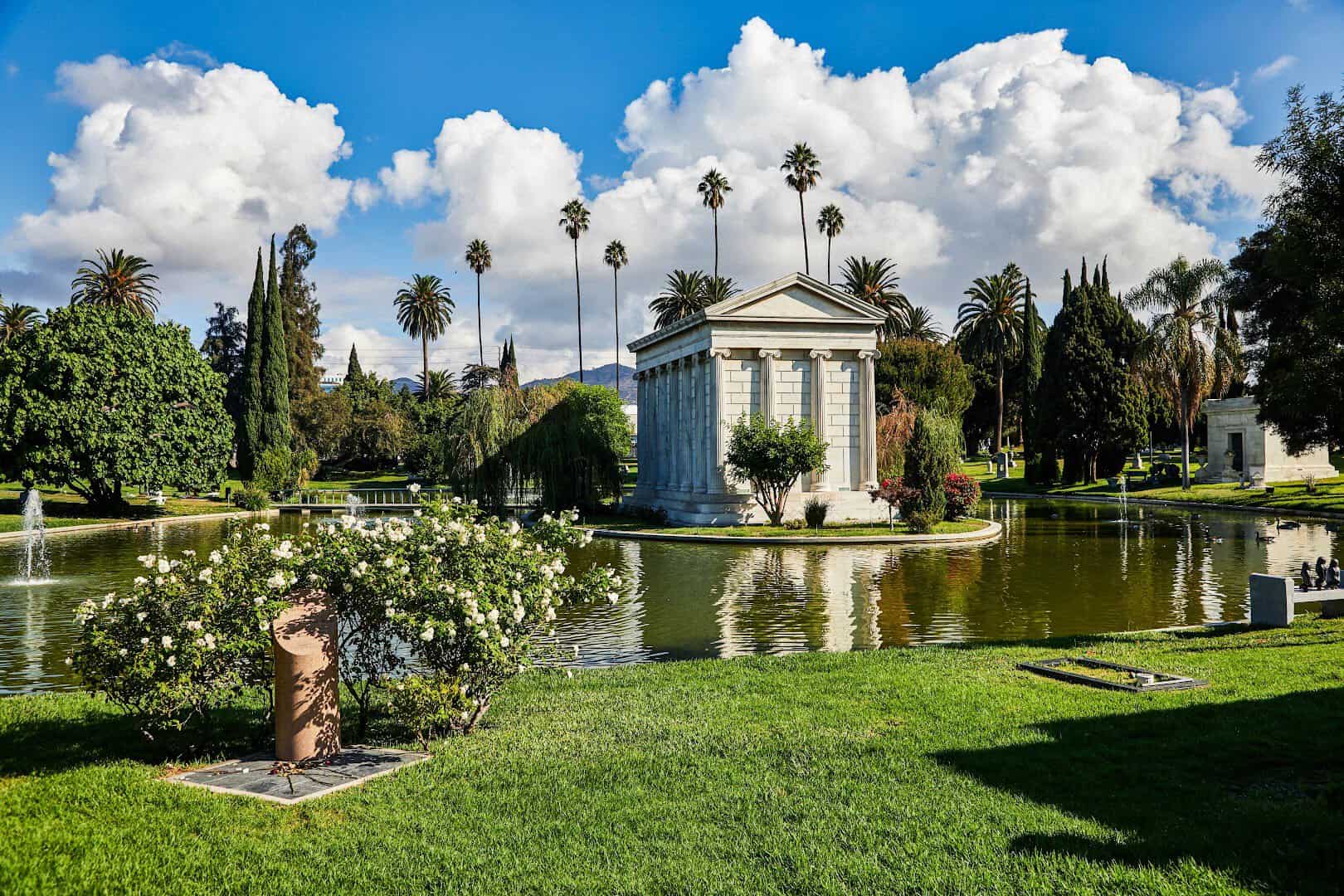Marble mausoleum reflected in the lake with palm trees at Hollywood Forever Cemetery in Los Angeles, California