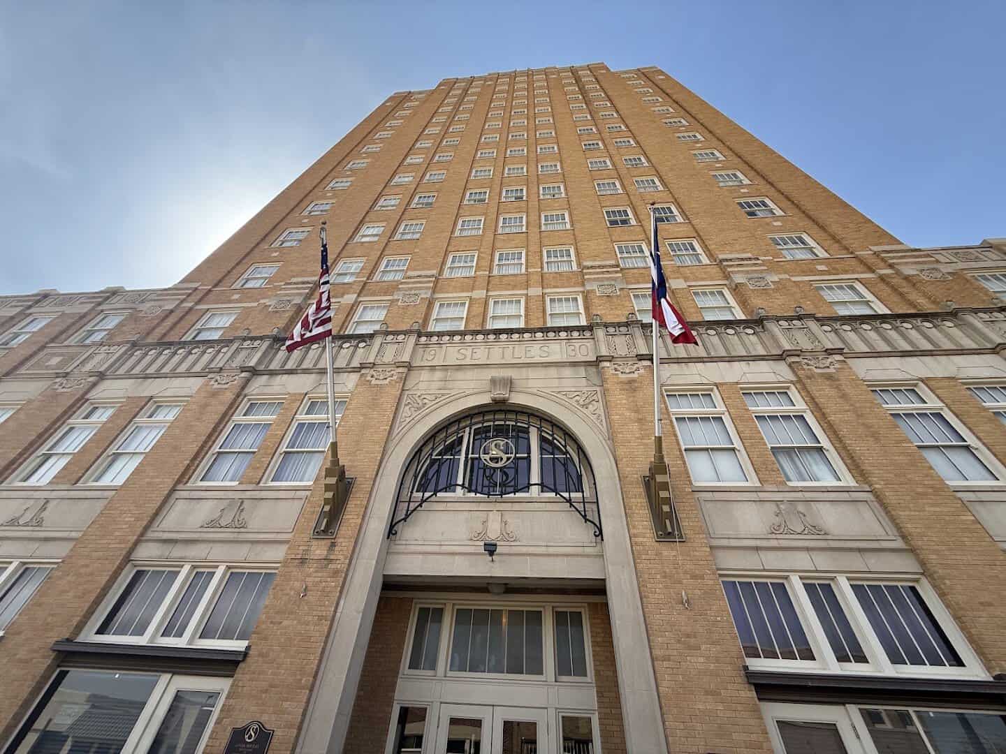 The Art Deco facade of Hotel Settles with the carved Settles 1930 datestone and flags in Big Spring, Texas