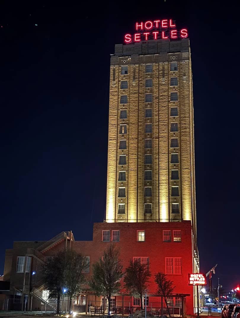 The Hotel Settles tower at night with its red neon sign glowing over Big Spring, Texas