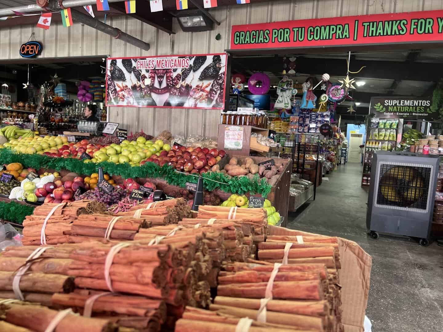 Busy produce aisle with vendor signs at the Houston Farmers Market in Houston