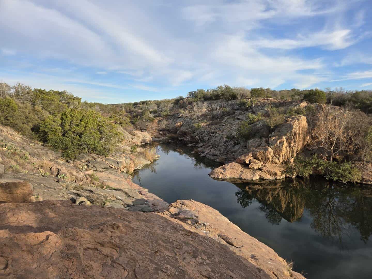 Pink granite cliffs ringing the cove at Devil's Waterhole in Inks Lake State Park