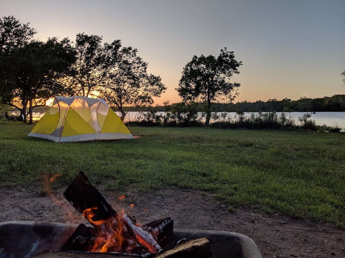 Tent and campfire at dusk beside the lake at Inks Lake State Park