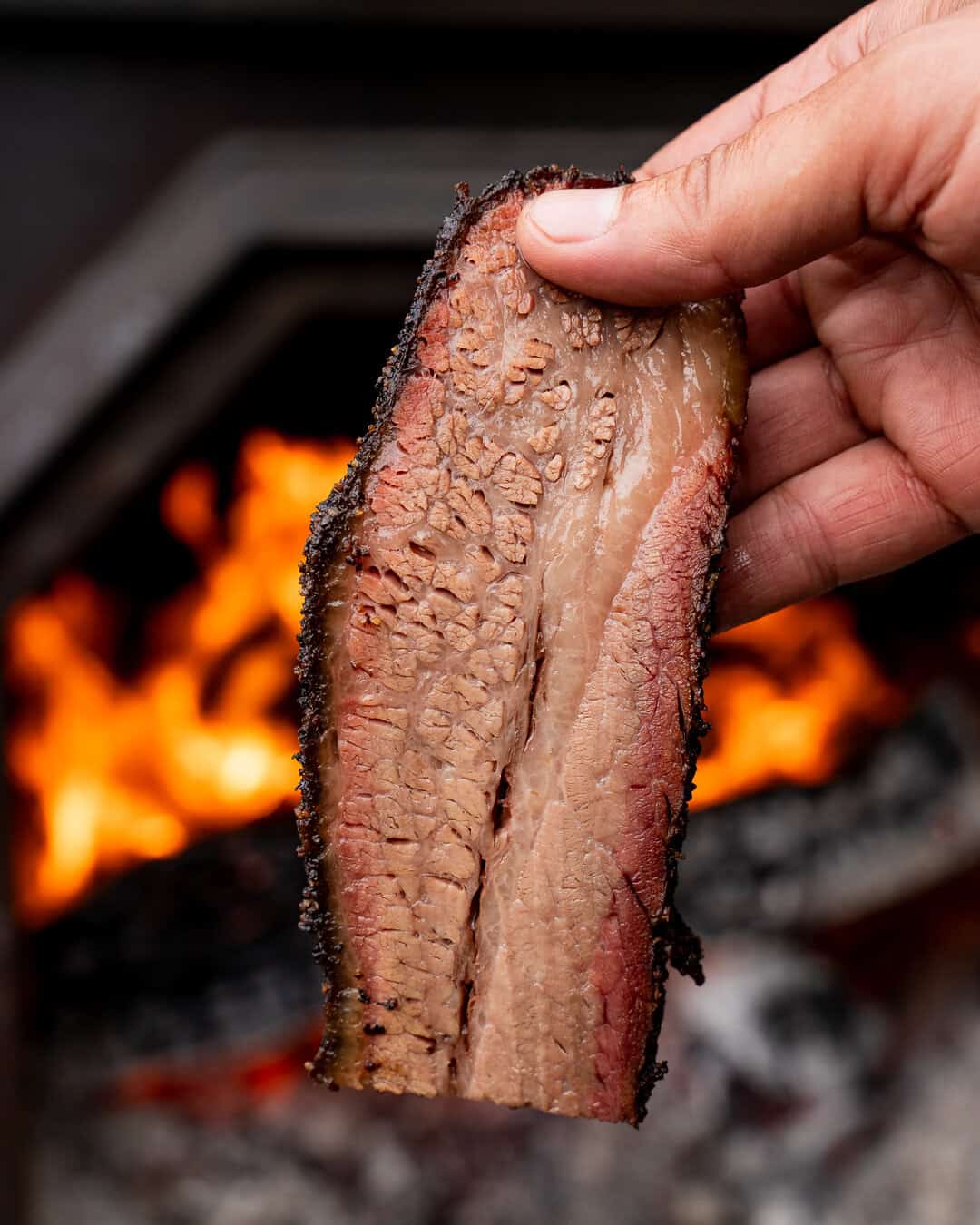 Slice of smoked brisket held over an open fire at InterStellar BBQ in Austin, Texas