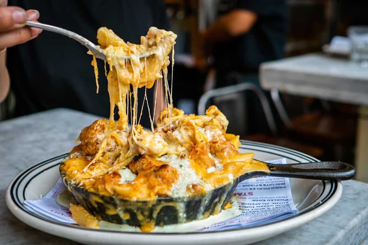 Skillet of gooey mac and cheese with a cheese pull at Jacob's Pickles in New York City
