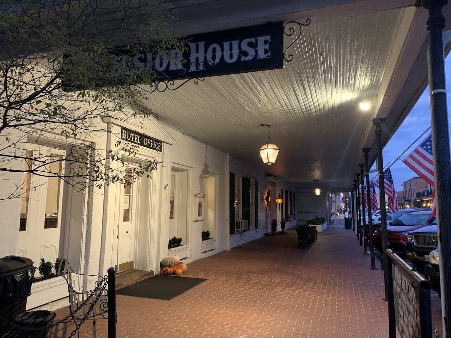 Historic Excelsior House porch lit at night with a jack-o-lantern in haunted Jefferson, Texas