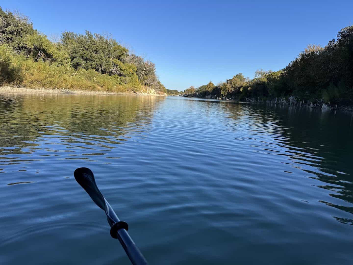 View over a kayak paddle on the calm water of Boerne City Lake in Boerne, Texas