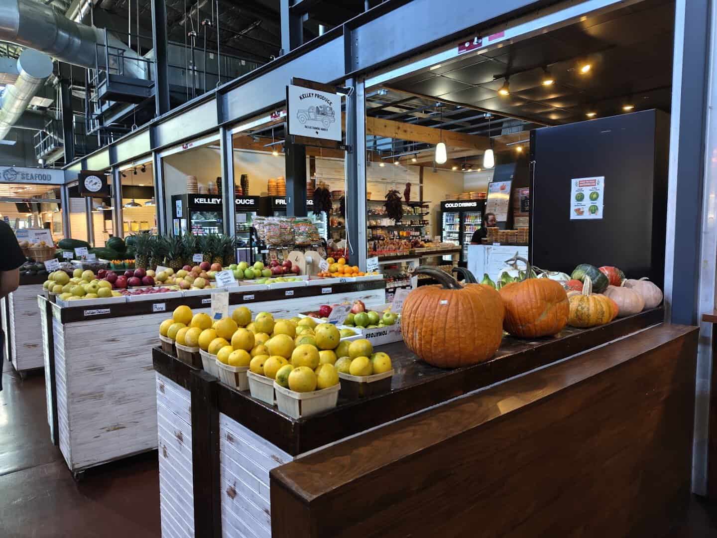 A produce stall piled with fruit and pumpkins inside the Dallas Farmers Market