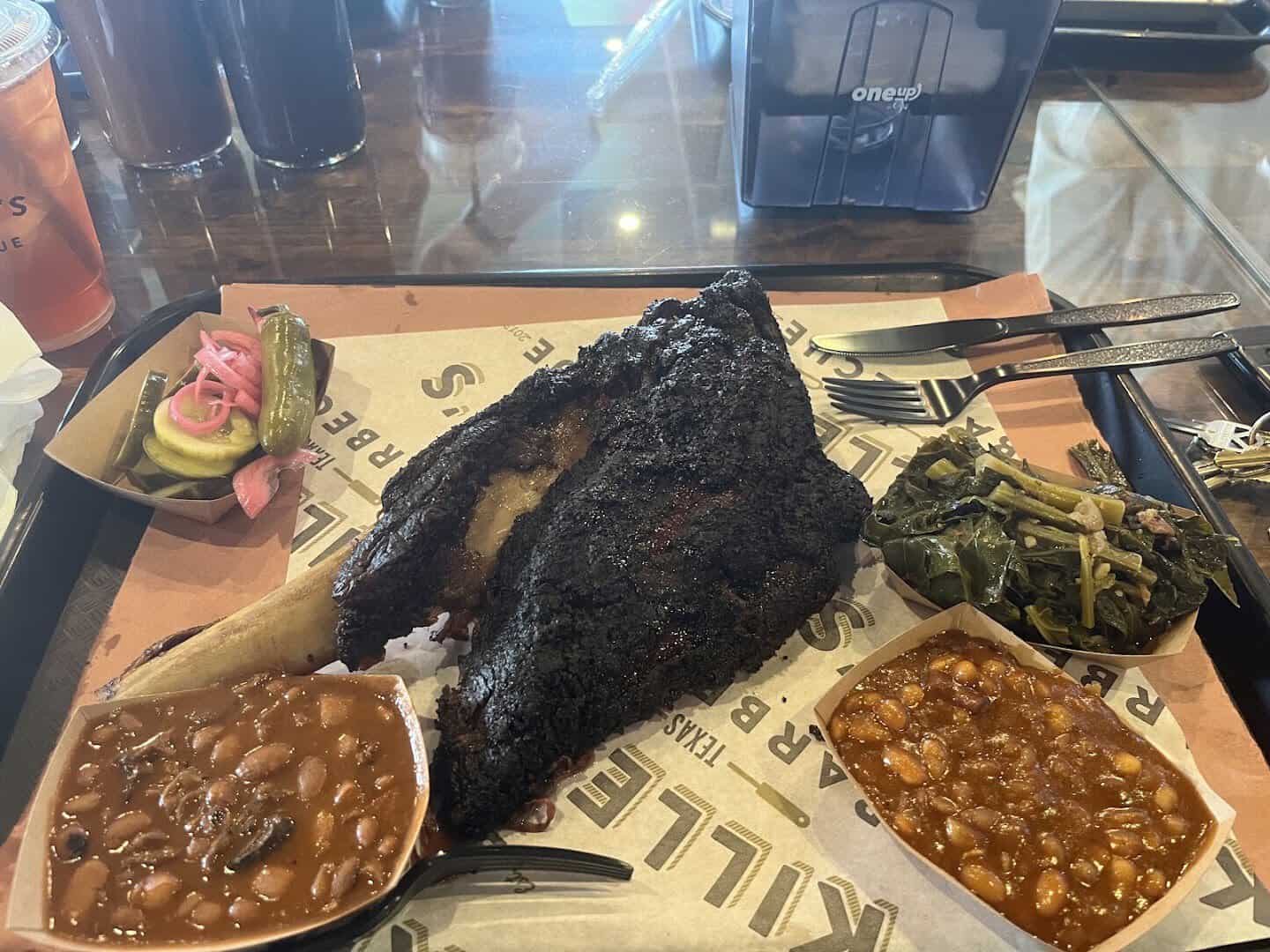 A giant smoked beef rib with beans and collard greens at Killen's Barbecue in Pearland, Texas
