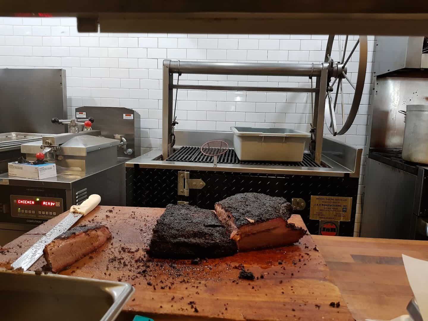 Smoked brisket resting on the brick pit inside Killen's Barbecue in Pearland, Texas