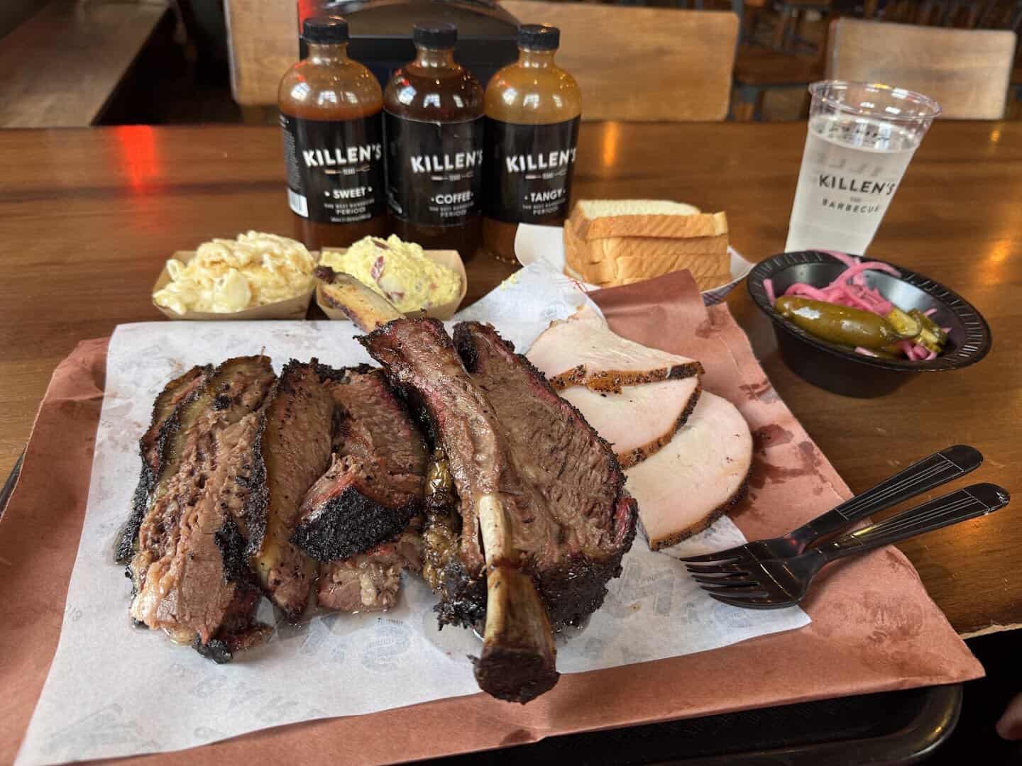 Beef rib, brisket, turkey and sausage plate with sauces at Killen's Barbecue in Pearland, Texas