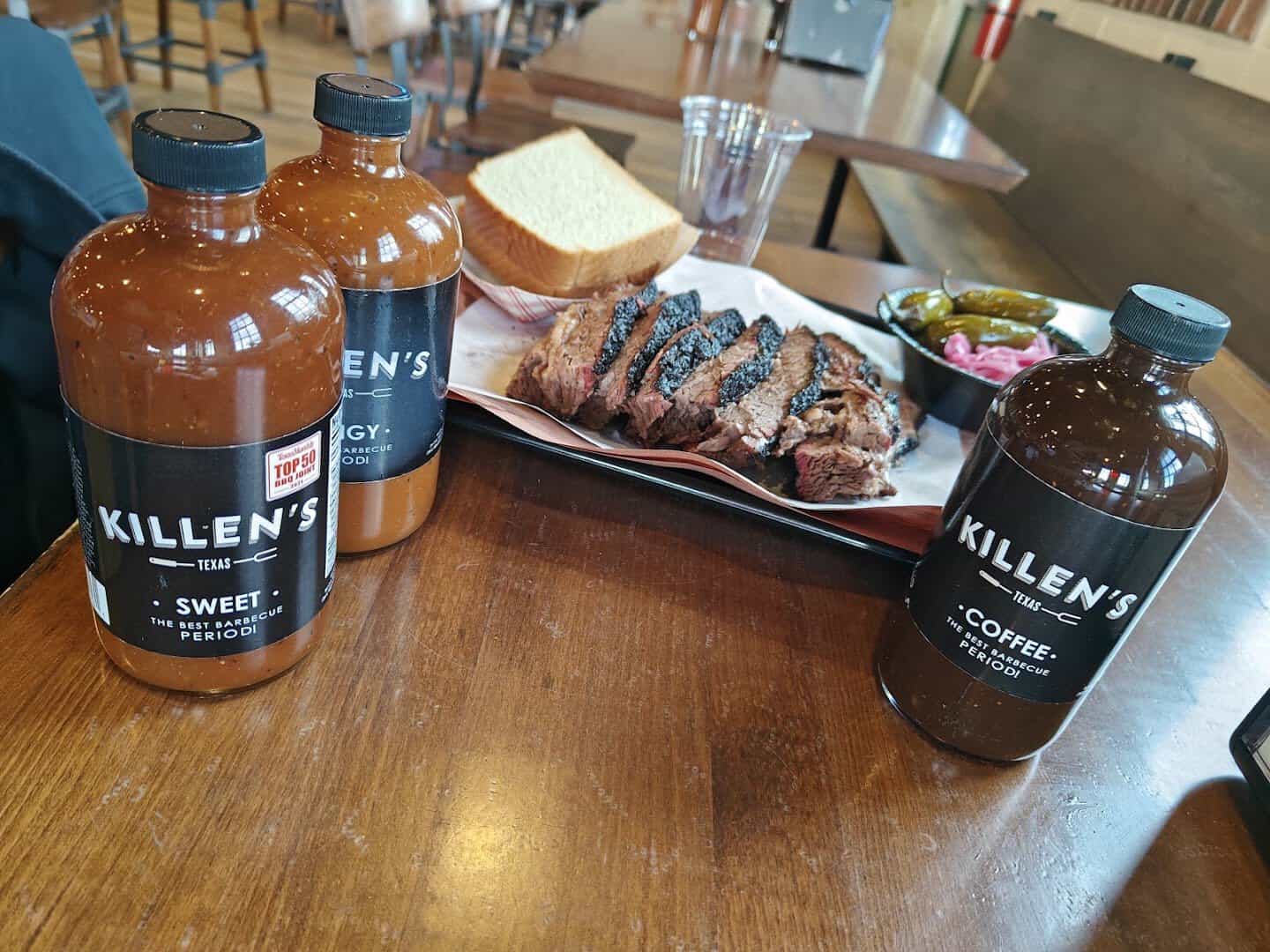 Killen's Barbecue sauce and coffee bottles beside a brisket tray in Pearland, Texas