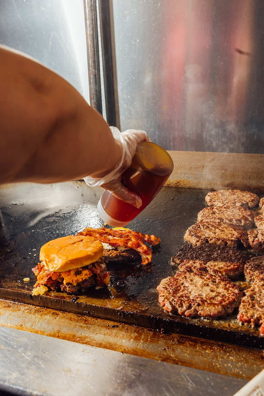 Cheeseburger with melting cheese cooking on the flat-top griddle at Kincaid's Hamburgers in Fort Worth