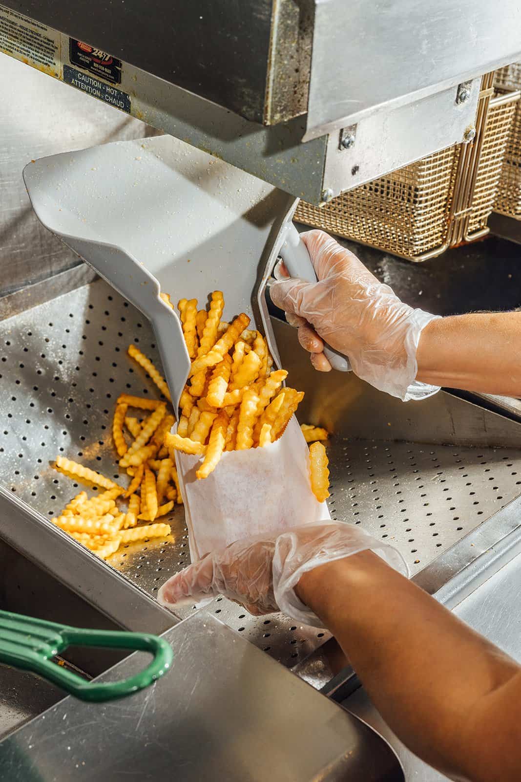 Crinkle-cut fries being scooped into a bag at Kincaid's Hamburgers in Fort Worth