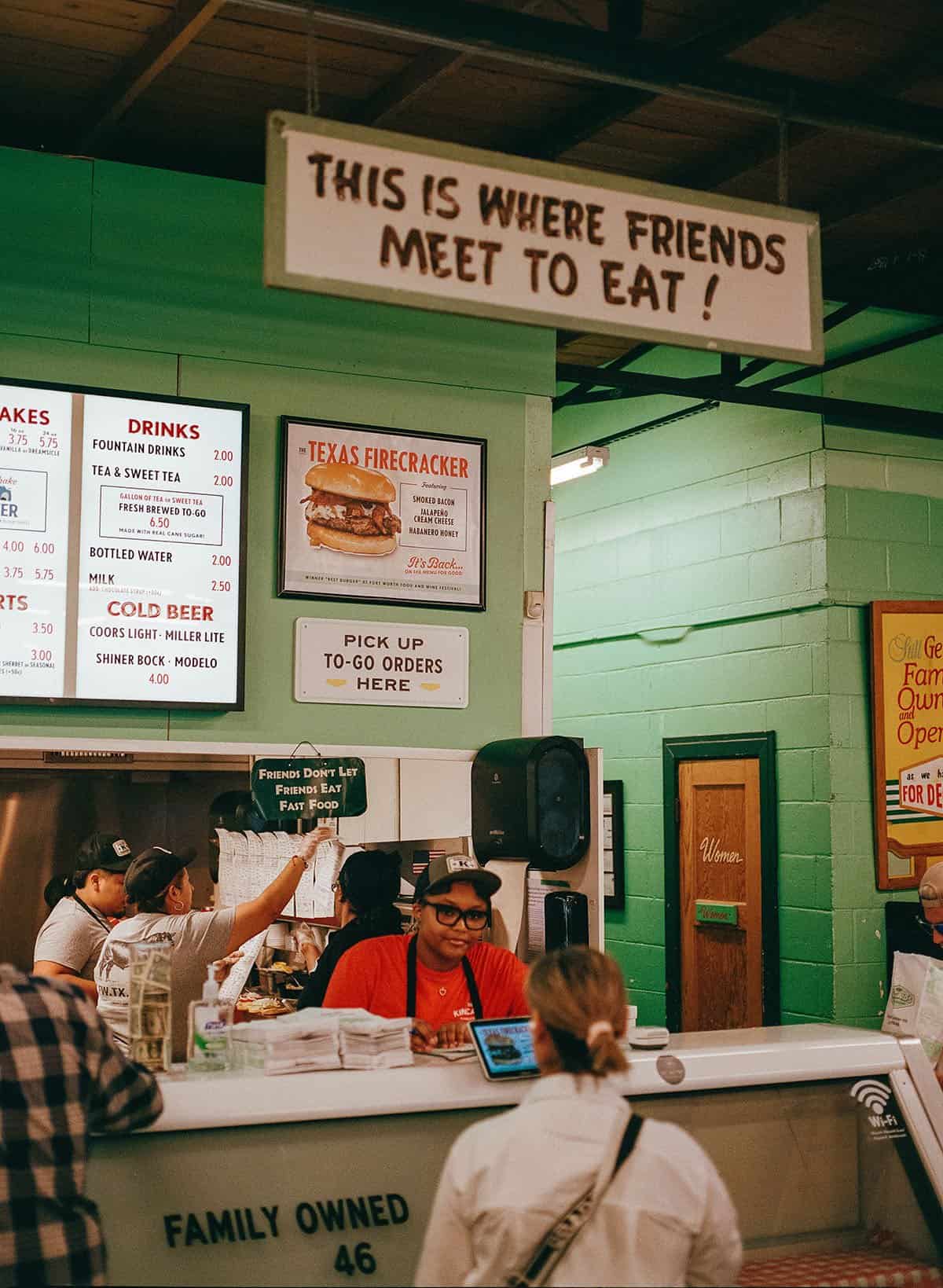 The This Is Where Friends Meet To Eat sign above the menu board at Kincaid's Hamburgers in Fort Worth