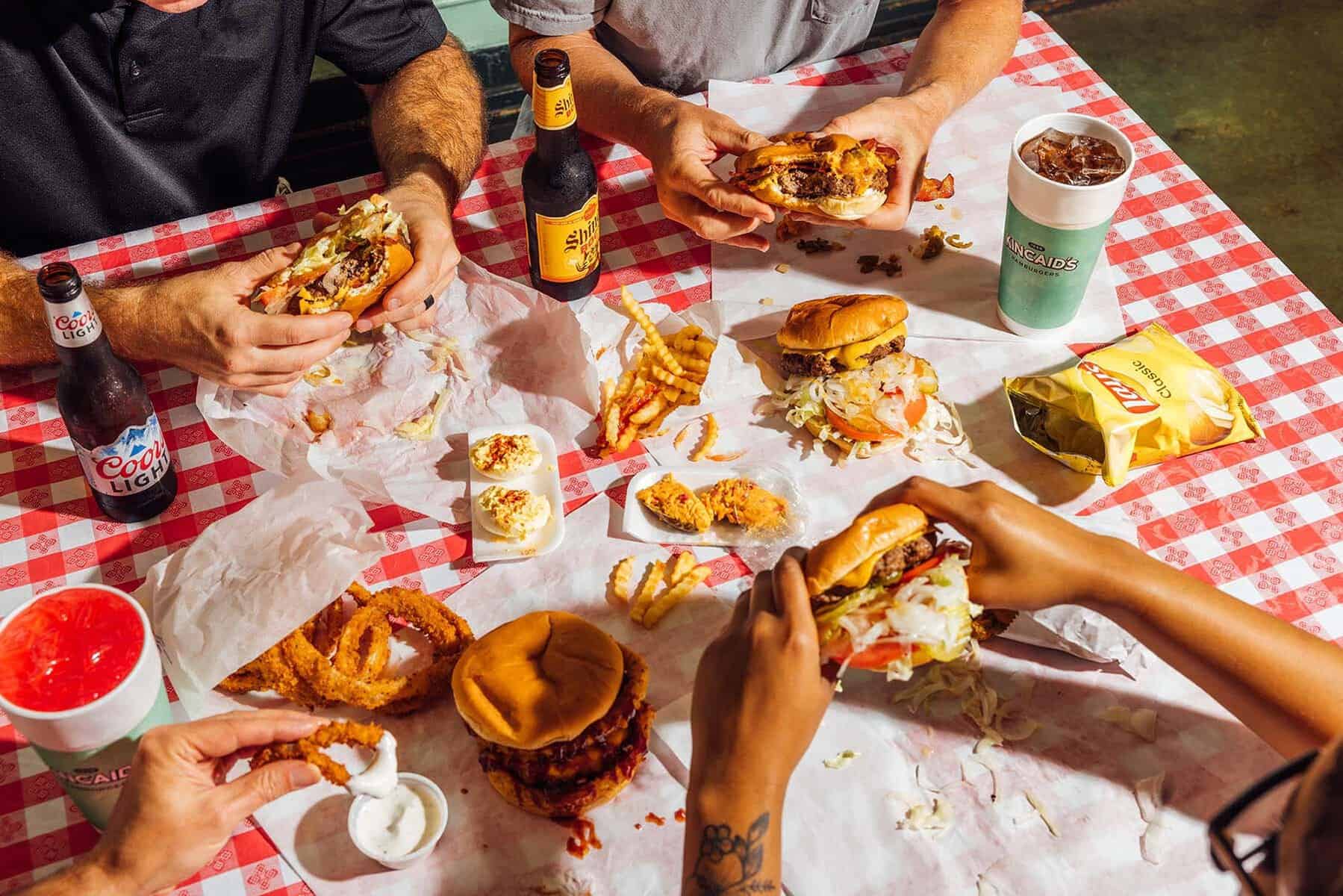 A spread of loaded half-pound burgers and sides at Kincaid's Hamburgers in Fort Worth