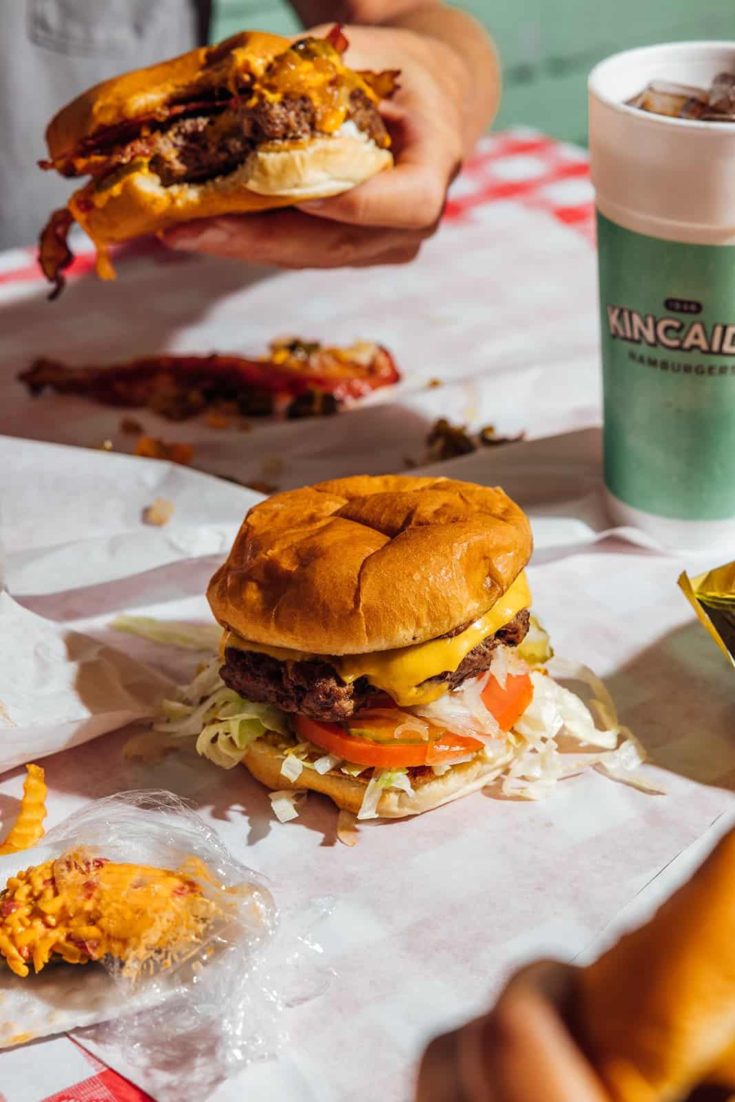 A hand holding a loaded half-pound cheeseburger at Kincaid's Hamburgers in Fort Worth