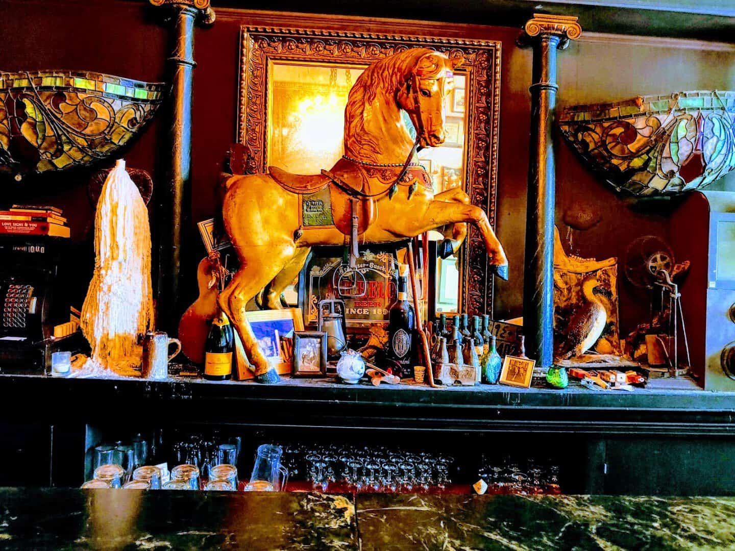 Antique back bar with carved carousel horse and mirror at La Carafe in Houston