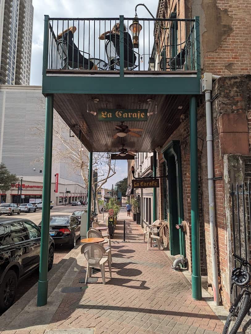 Second floor balcony and La Carafe sign above the sidewalk in Houston