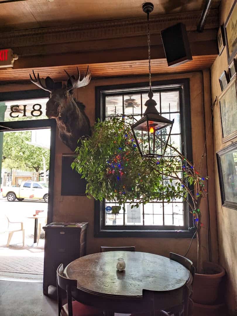 Cozy candlelit corner with a hanging lamp inside La Carafe in Houston
