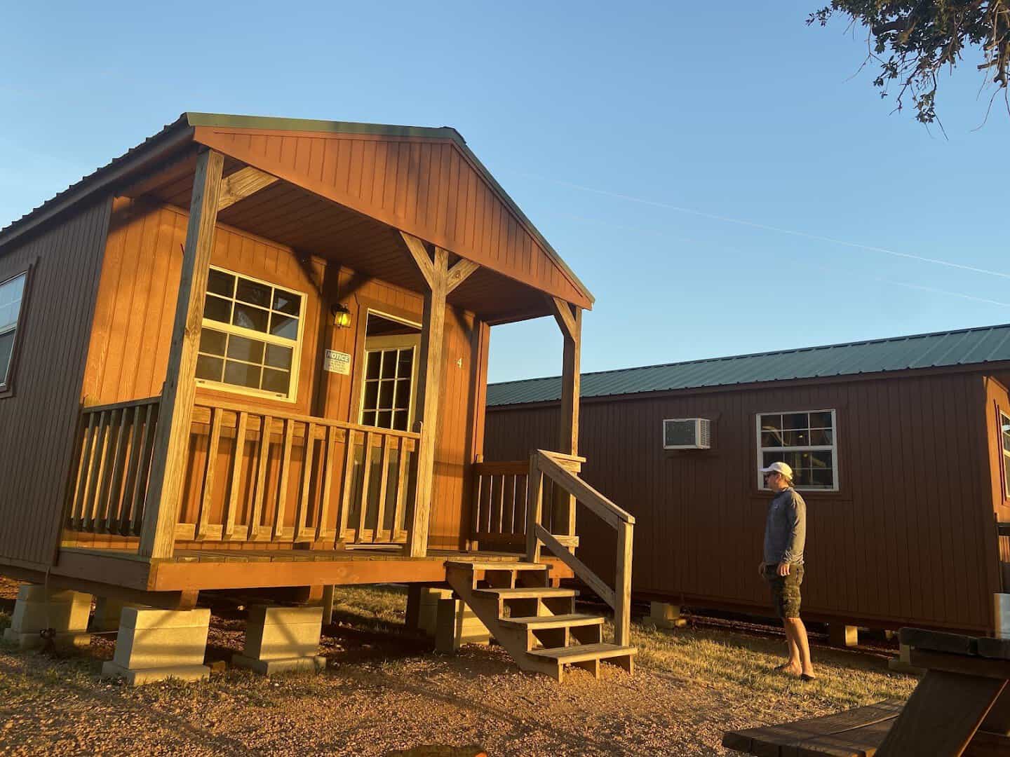A tiny log cabin with a covered porch at Lake Buchanan RV and Cabin Resort in Burnet, Texas