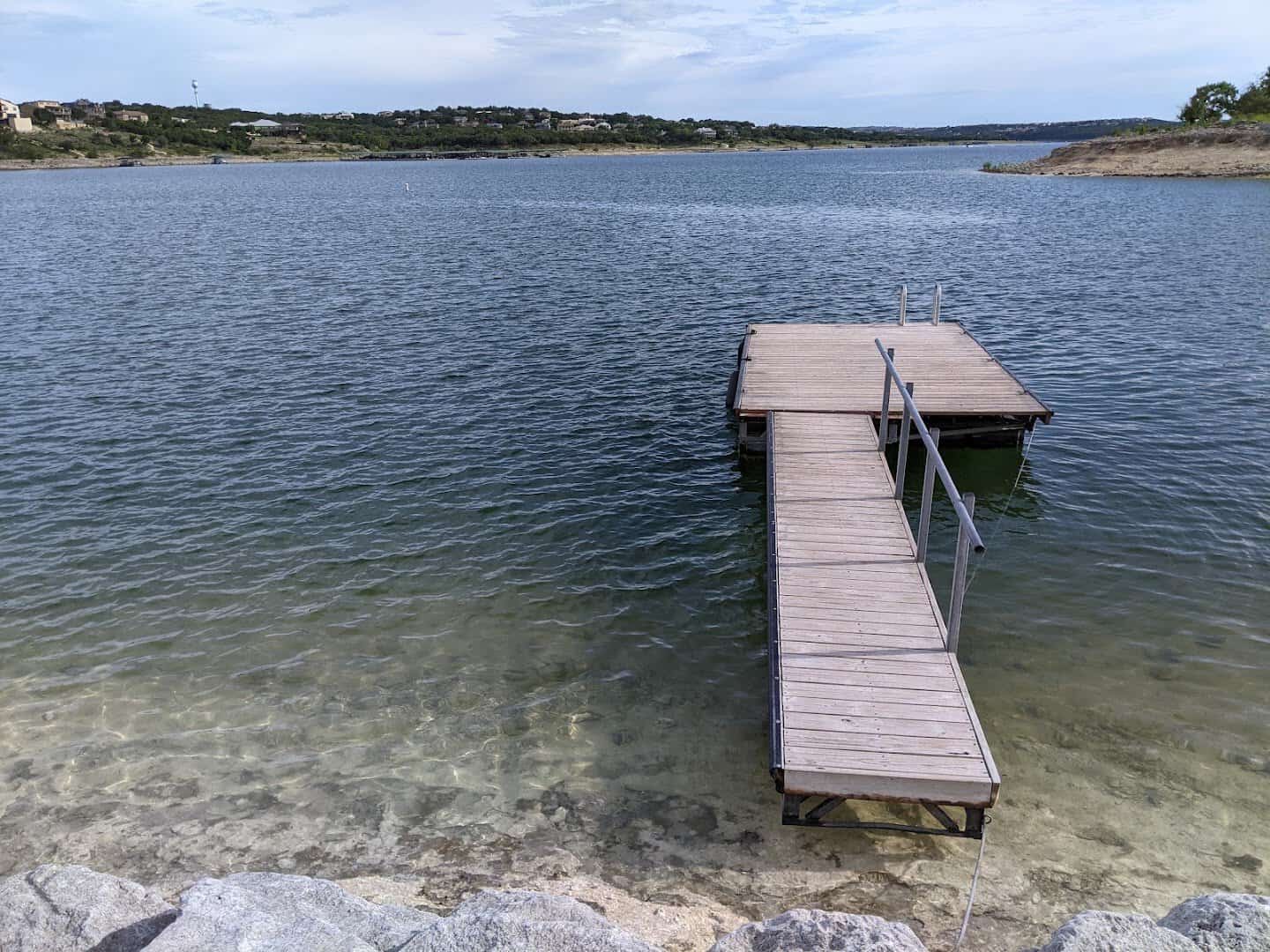 Wooden dock reaching into shallow, clear water on Lake Travis