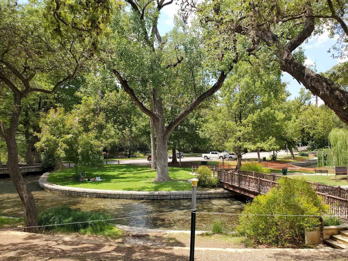 Shaded walkway beside the water under old trees at Landa Park in New Braunfels, Texas