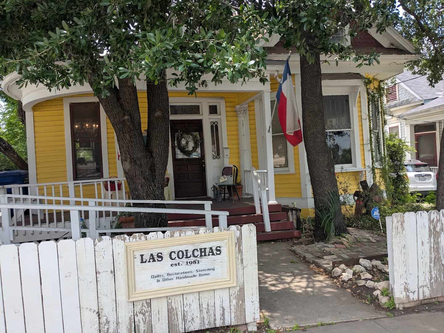 Las Colchas quilt shop sign on the yellow 1920s house in San Antonio