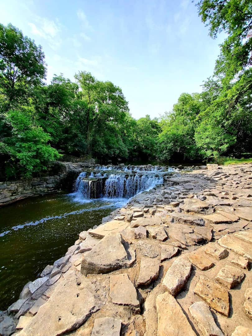 Layered rock ledges forming the stepped cascade at Prairie Creek Park in Richardson, Texas